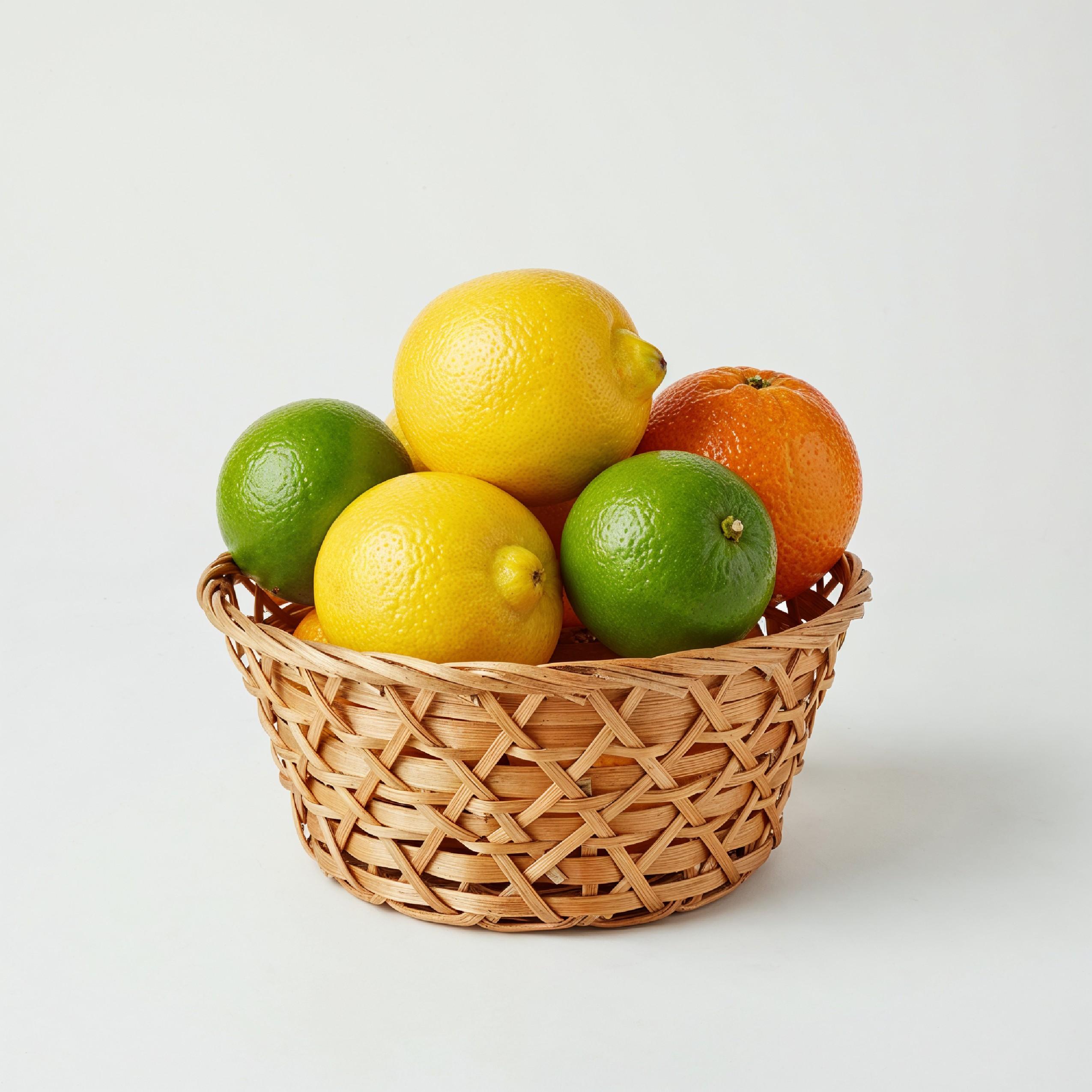Small Wicker Basket Filled with Fresh Citrus Fruits Isolated on White Background