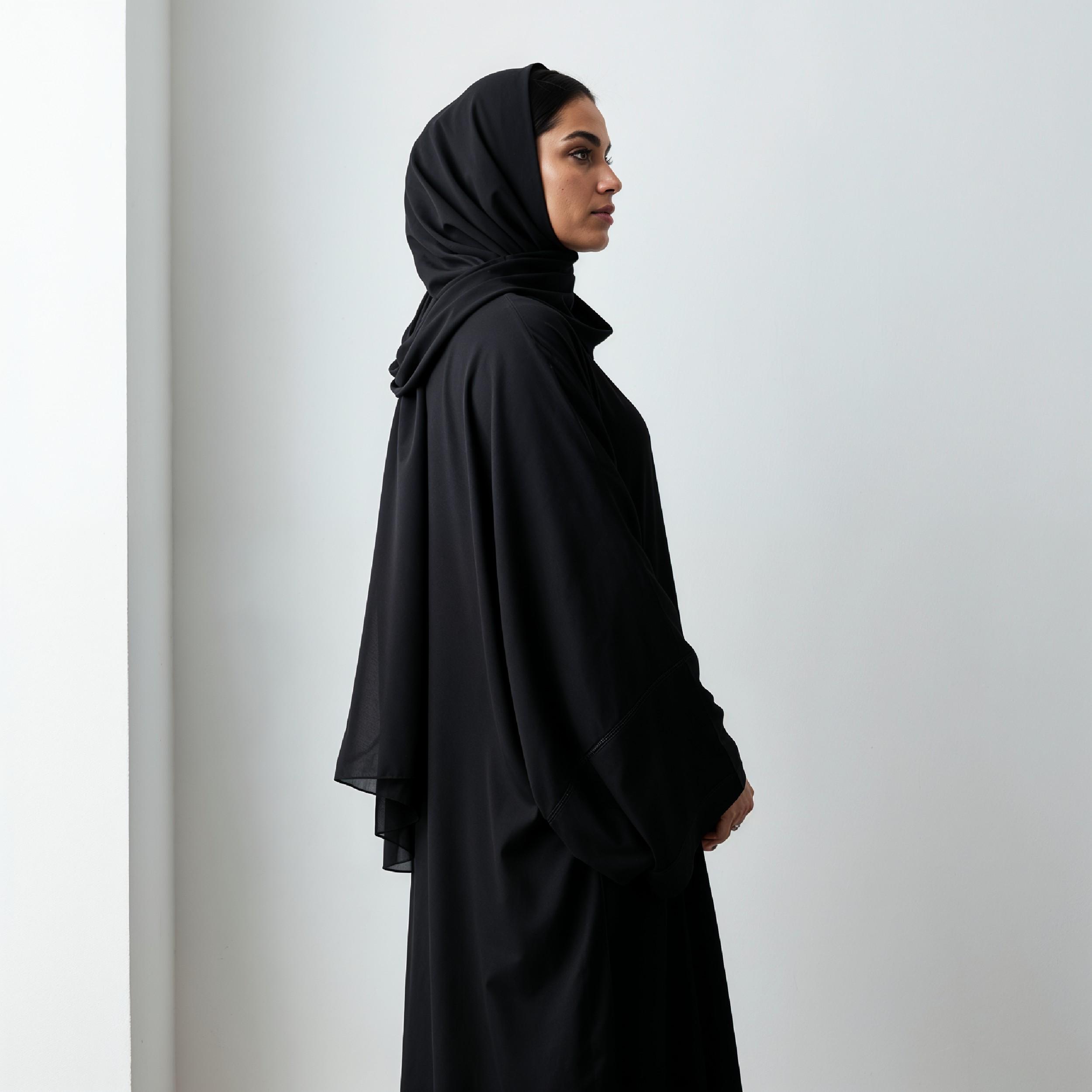 Elegant Muslim Woman Wearing Black Hijab and Abaya in Studio Portrait on Light Background