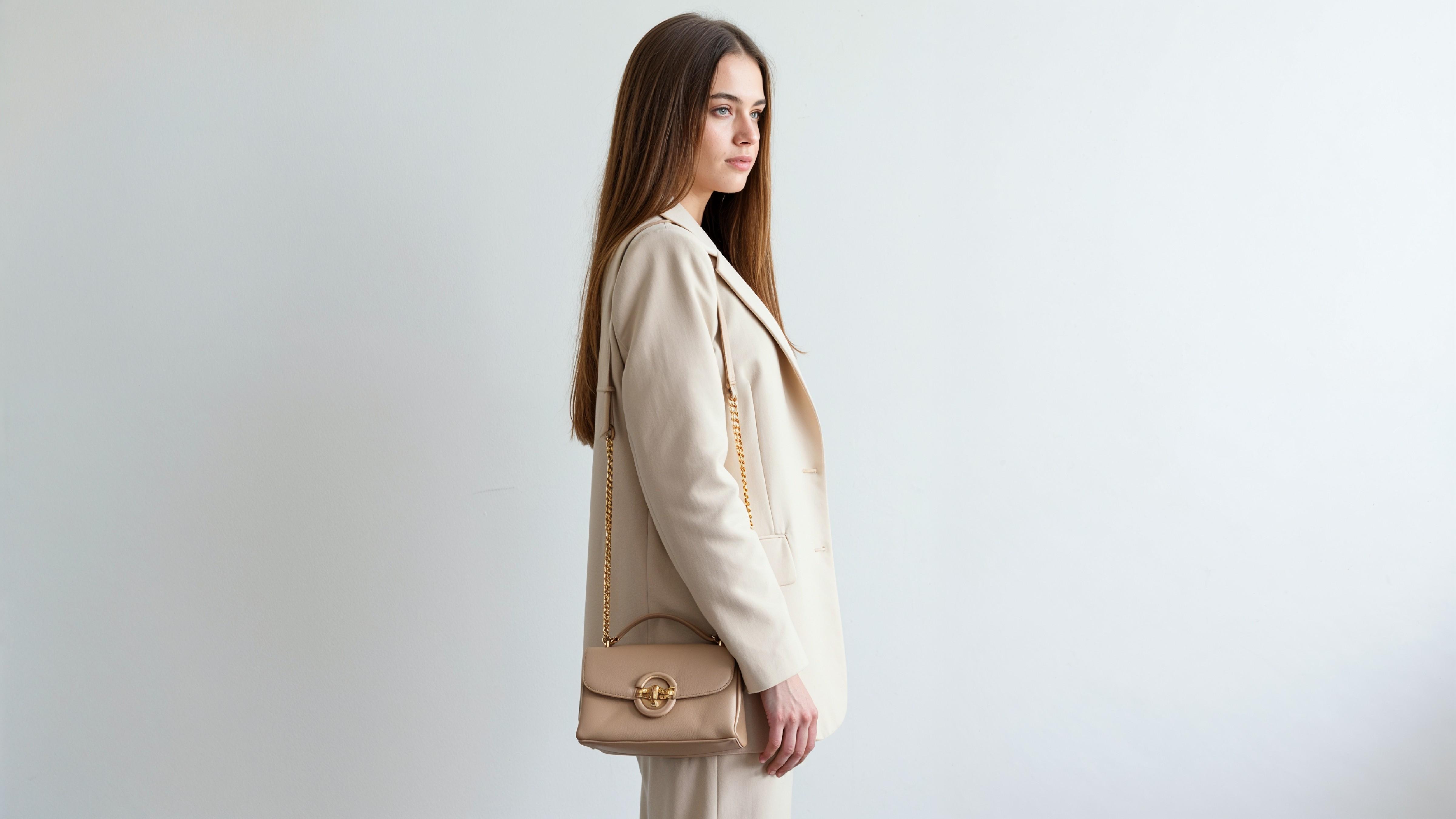 Trendy Young Woman Wearing Cream Coat Pant Suit with Leather Handbag